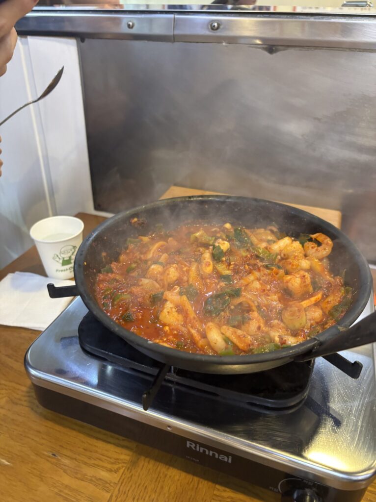 たこ・ホルモン・えびが入ったナッコプセ鍋を火にかけている写真